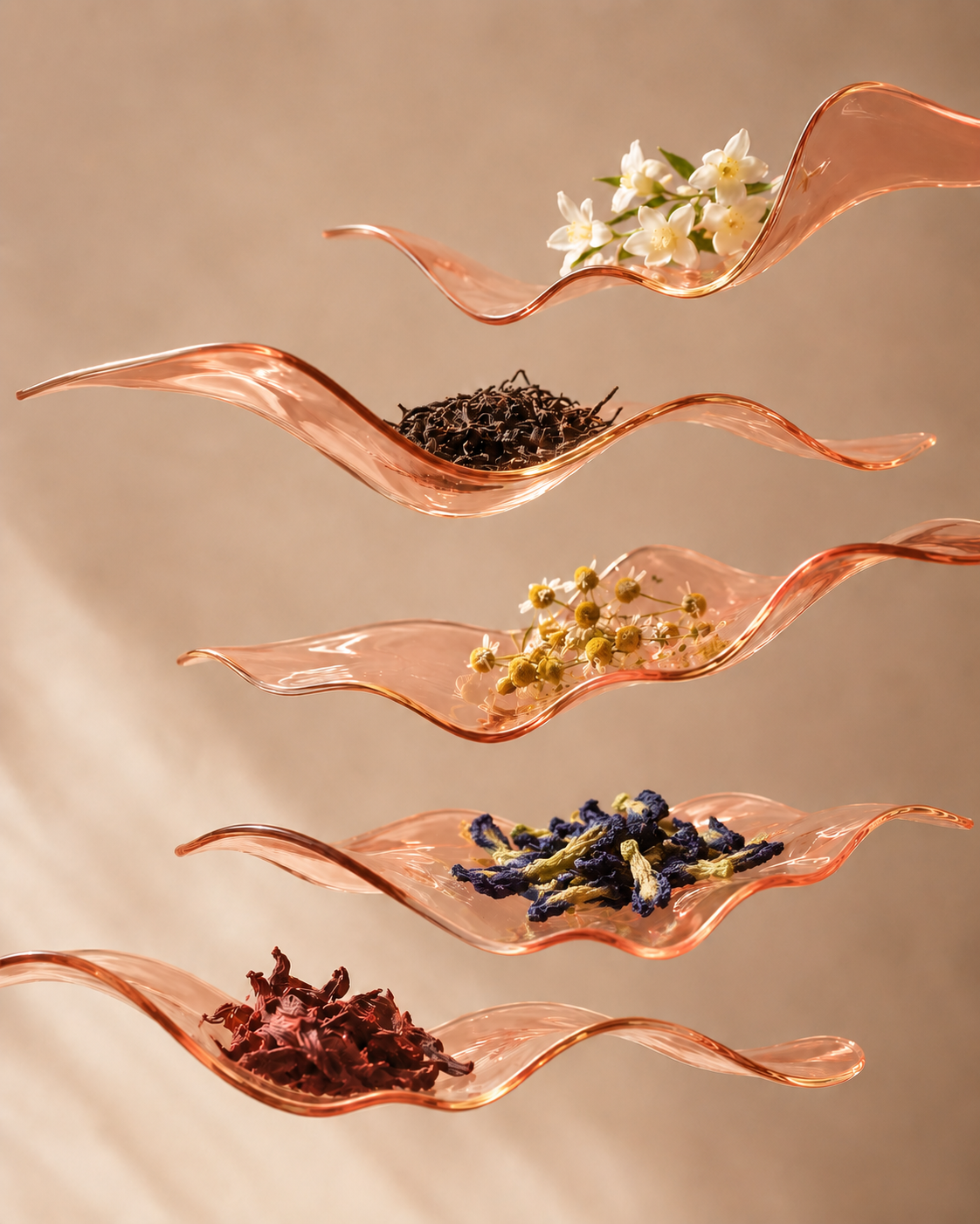 Glass wave dishes holding tea leaves, jasmine, chamomile, butterfly pea, and hibiscus